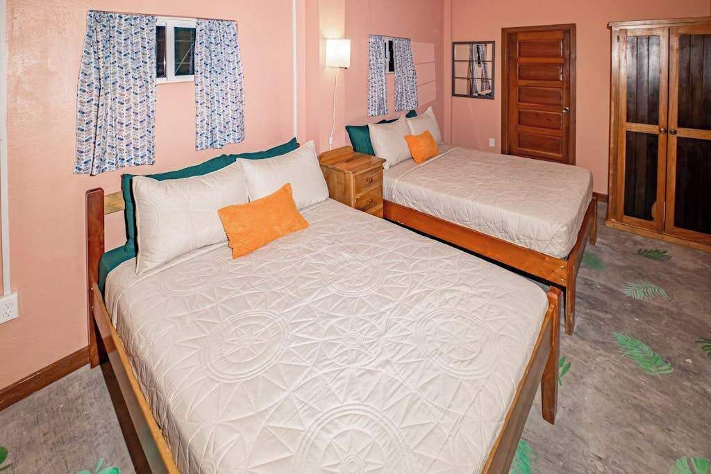 Una habitación con dos camas, un armario de madera y cortinas estampadas.