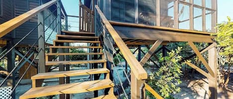 A wooden staircase leading to a glass-enclosed upper level of a building.