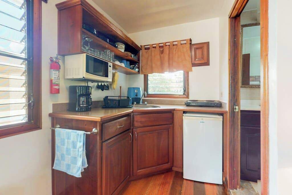 A compact kitchen with wooden cabinets, a microwave, a coffee maker, and a refrigerator.