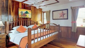A wooden-framed bed with a headboard, a ceiling fan, and artwork on the walls.