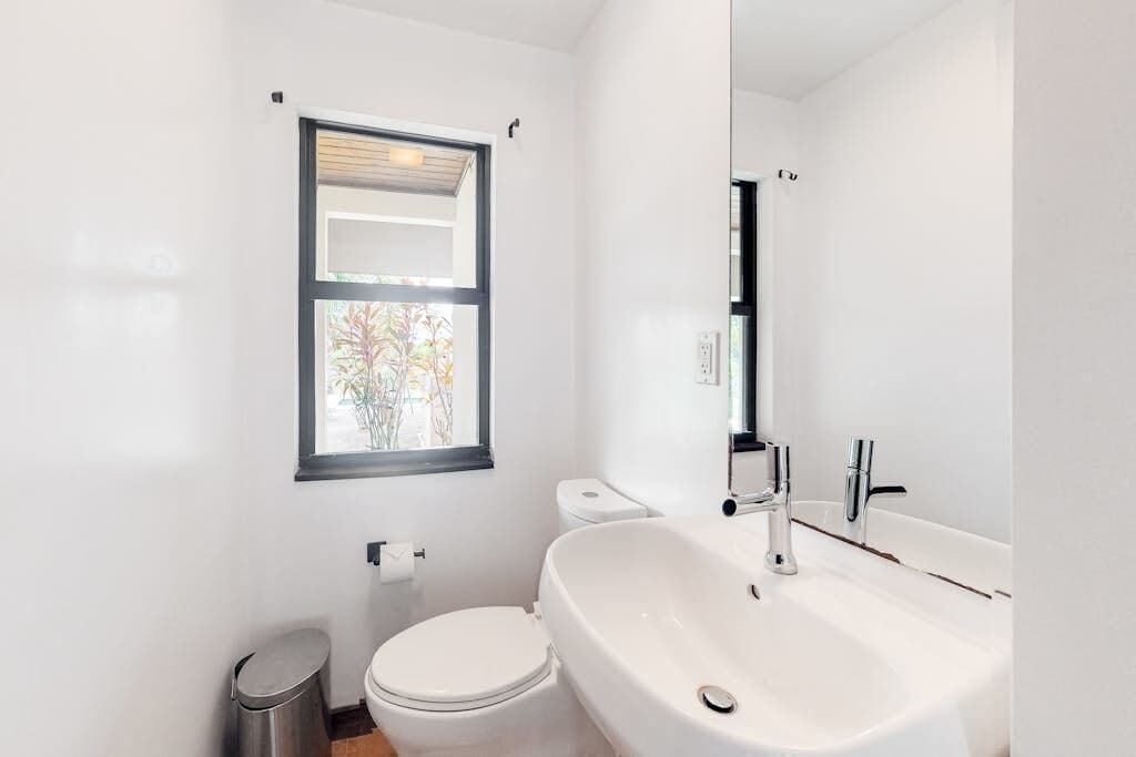 Un baño moderno con inodoro, lavamanos y ventana.
