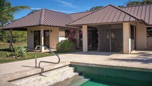 Ein modernes Haus mit Pool, überdachter Terrasse und gepflegtem Garten.