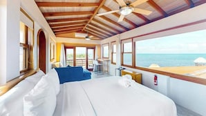 Ein Schlafzimmer mit einem großen Bett, einem Deckenventilator und Blick auf den Strand.