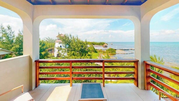 Ein Balkon mit Blick auf eine Küstenlandschaft, einschließlich eines Hauses und dem Meer.