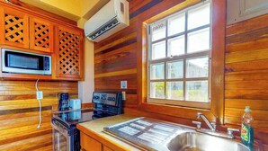 Une cuisine avec des meubles en bois, un four à micro-ondes, une cuisinière, un évier et une fenêtre.