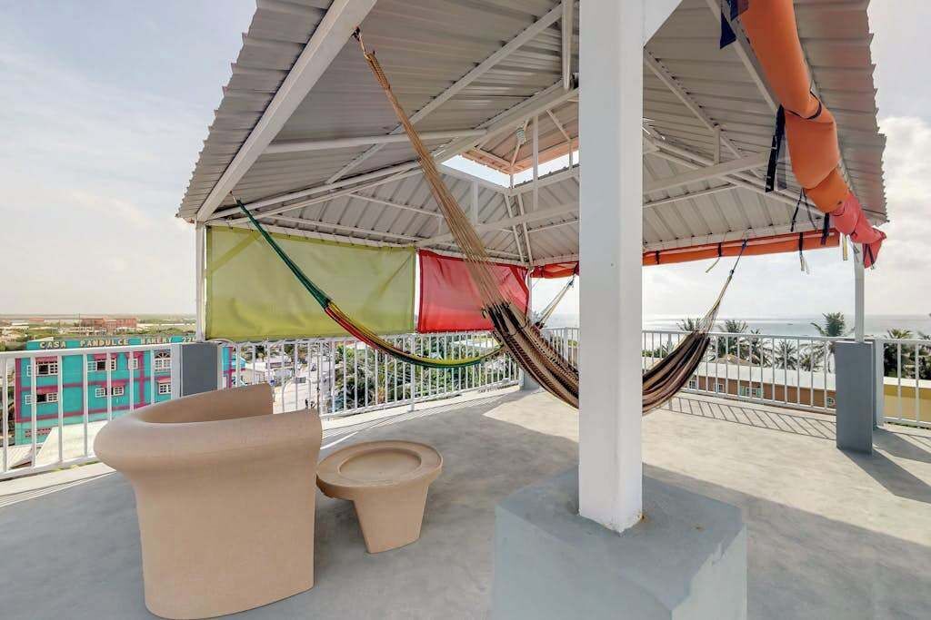 Een dakterras met een hangmat, een beige bank en een kleine tafel.