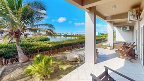 A covered outdoor area with a pool, palm trees, and a view of the water. - Vibrant, colorful lagoon-front suite with pool access, scenic patio, & WD (San Pedro)