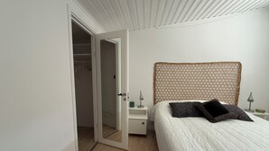 Un dormitorio con cama, mesita de noche, lámpara de noche, armario y puerta abierta que da a un vestidor.