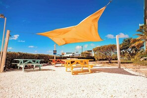A beachside area with picnic tables and a large yellow shade sail. - Oceanfront home with pool, breathtaking views, central AC & 2 large balconies (San Pedro)