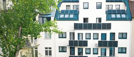 A multi-story building with solar panels on the roof and balconies.