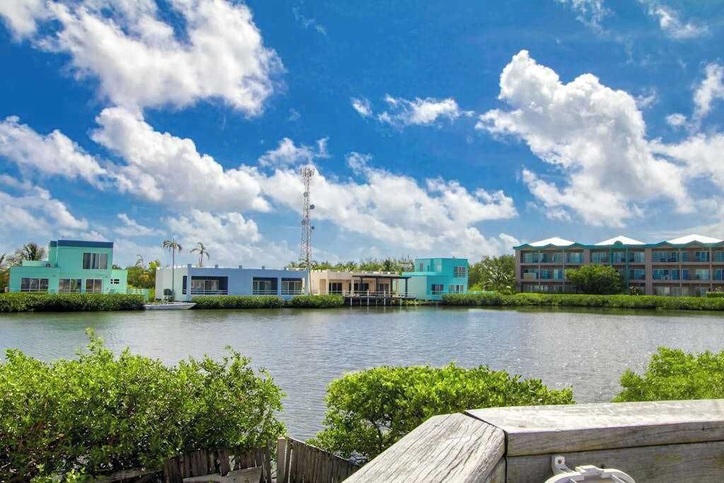 Ett hotell vid vattnet med flera byggnader, en brygga och en klar himmel.