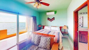A room with a bed, a ceiling fan, a window with a view, and a door. - Waterfront resort villa with water views, balcony, full kitchen, & washer dryer (San Pedro)