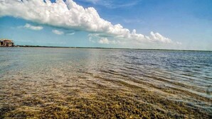 A coastal scene with clear water, a distant building, and a partly cloudy sky. - Waterfront resort villa with water views, balcony, full kitchen, & washer dryer (San Pedro)