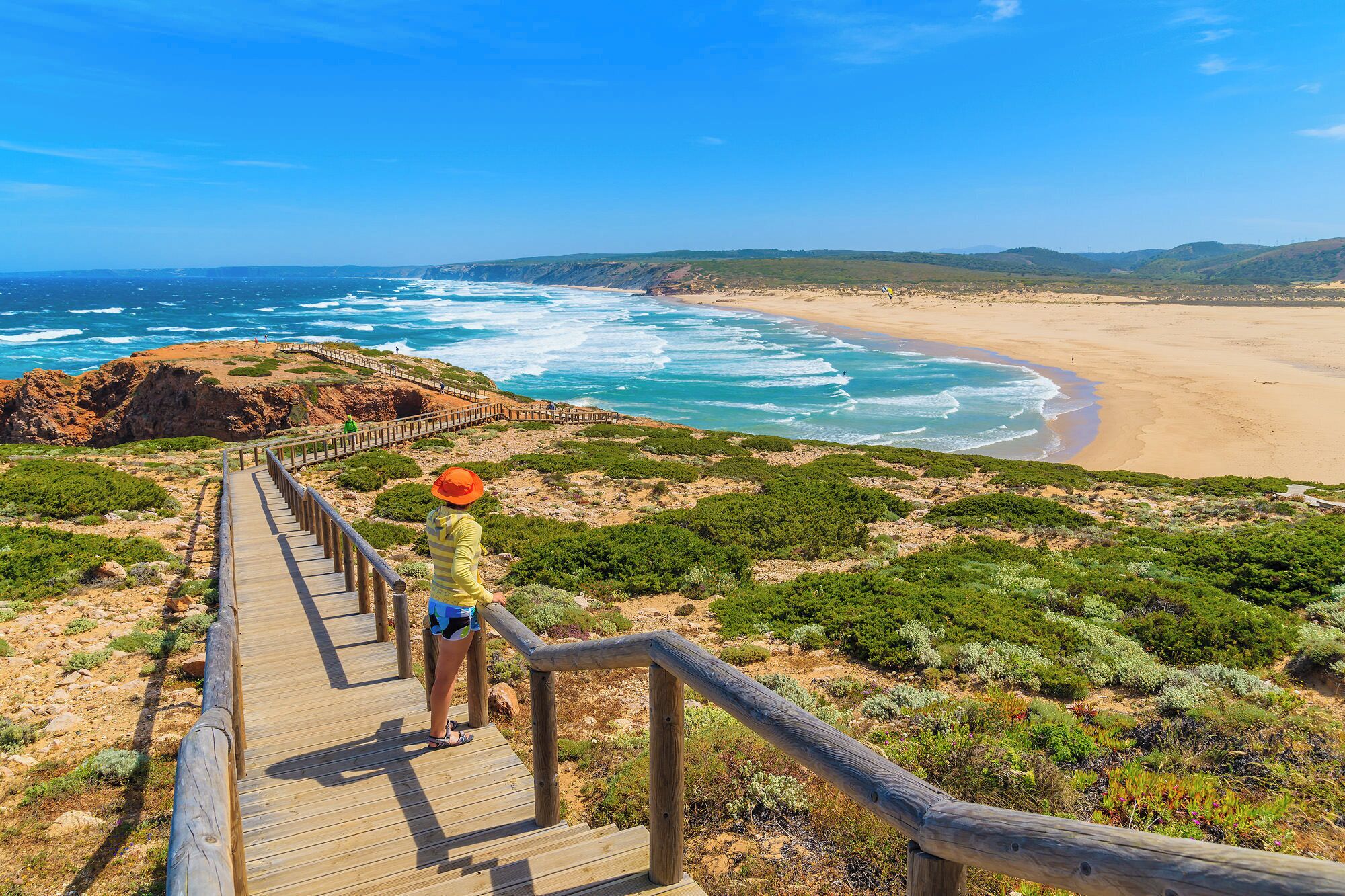 A wooden boardwalk leading to a beach with ocean views.