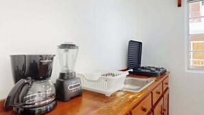 A kitchen with a blender, coffee maker, and a gas stove. - Enchanting single-level living space with a mini kitchen in a prime area (Caye Caulker)