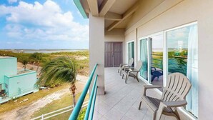 A balcony with a view of the ocean, a door, and a seating area with chairs. - Renovated 2BR with Sunset Views at Mara Laguna (San Pedro)
