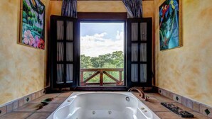 Ein Zimmer mit einer großen Badewanne, einem Holzboden und zwei Bildern.