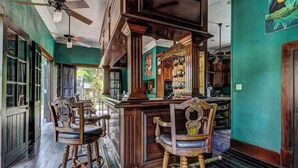 Ein Barbereich mit Holzkästen und einer Bar, grünen Wänden und einem Deckenventilator.