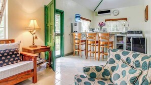 Un espacio habitable compacto con sofá, una mesa de comedor con sillas, una zona de cocina y una puerta verde.