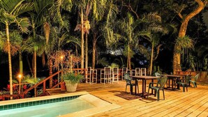 A wooden deck with outdoor seating, a pool, and tropical vegetation. - Riverfront Suite, Lovely View, Partial AC, WiFi & Pool (San Ignacio)
