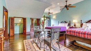 A bedroom with a bed, two chairs, a table, a ceiling fan, and a window. - Riverfront Suite, Lovely View, Partial AC, WiFi & Pool (San Ignacio)