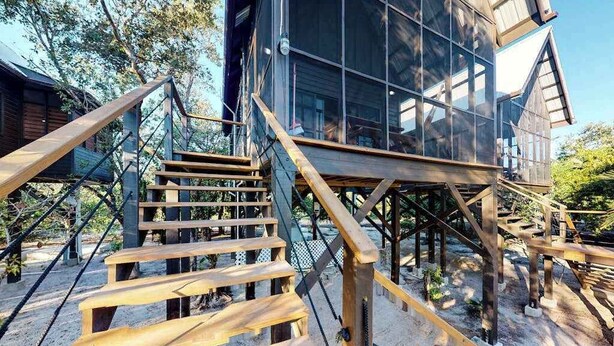 A wooden staircase leading to a glass-roofed building with a wooden deck.