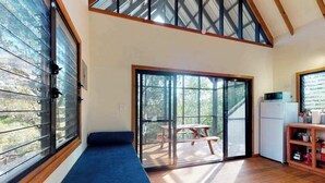 A room with a bench, a sliding glass door leading to a deck, and a kitchenette.