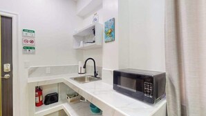 Una cocina compacta con microondas, lavabo y estantes de almacenamiento.
