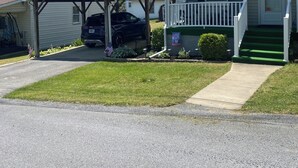 Ein zweistöckiges Haus mit überdachter Garage, einer Veranda und einem grünen Rasen.