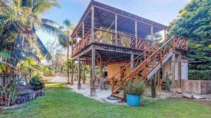 Ein teilweise errichtetes Holzgebäude mit Treppe, umgeben von einem Rasen und Palmen.