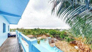 Un complexe hôtelier doté d’un bâtiment bleu, d’un espace piscine avec un toboggan aquatique et d’une végétation tropicale.
