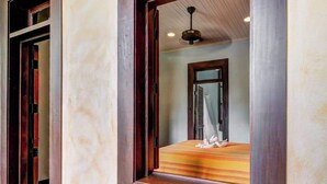 Um quarto com uma cama de madeira, janela com vista e ventilador de teto.