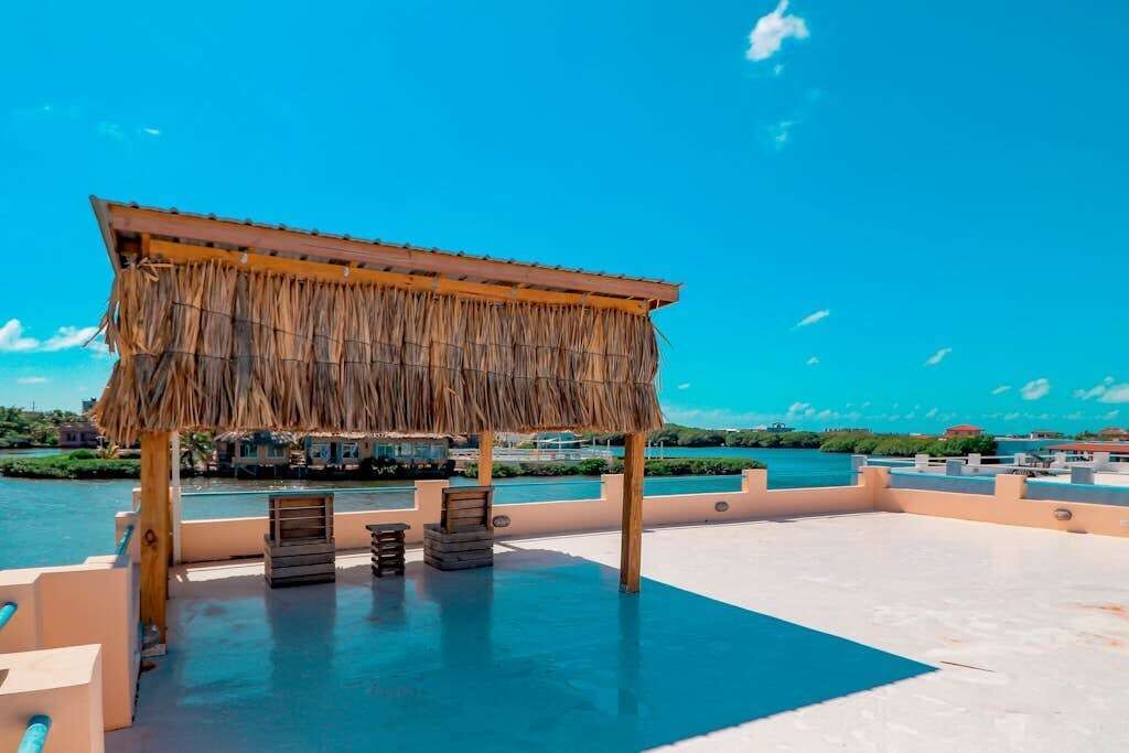 Eine Dachterrasse mit strohgedecktem Bauwerk, Sitzgelegenheiten und Blick aufs Meer.