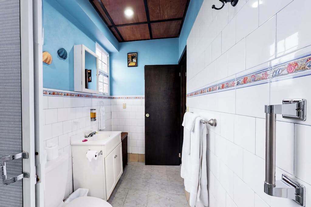 A bathroom with a blue accent wall, white tiles, a black door, and a towel rack.