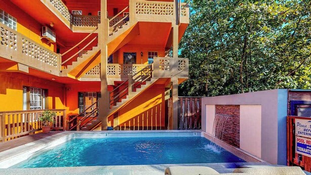 Un edificio de varios pisos con piscina, mobiliario exterior y una escalera.