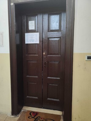 A wooden double door with a doormat and a notice on the door. - CasaRì Vacation Rental – Apartment in the Heart of Bari (Bari)