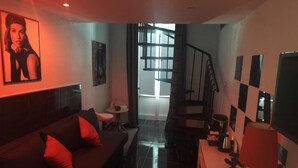A living room with a sofa, a coffee table, a TV, and a staircase leading to another level. - CasaRì Vacation Rental – Apartment in the Heart of Bari (Bari)