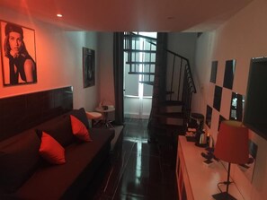 A living room with a sofa, a coffee table, a TV, and a staircase leading to another level. - CasaRì Vacation Rental – Apartment in the Heart of Bari (Bari)