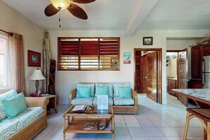 A living room with a sofa, coffee table, and a ceiling fan. - Ocean-view condo with pool, immediate beach access & partial AC (San Pedro)