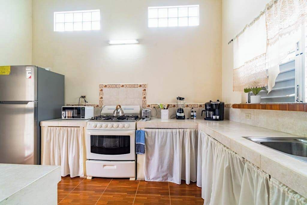 A kitchen with a refrigerator, microwave, stove, oven, and sink.