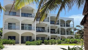 Un hôtel à plusieurs étages doté de balcons, d’un espace piscine et d’un aménagement paysager de style tropical.