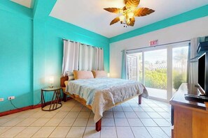 A bedroom with a bed, a small table, a ceiling fan, and an exit sign. - Lagoon front apartment w shared pool - two minutes from the beach (San Pedro)