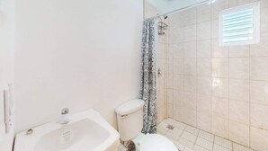 Een badkamer met bad, toilet en douchegordijn.