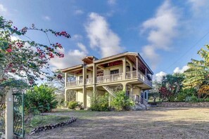 A two-story house with a balcony, surrounded by tropical vegetation. - A new home in a great neighborhood w WiFi, AC - near Maya ruins (San Ignacio)