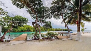 Une plage avec une jetée en bois, des palmiers et une vue sur l’océan.