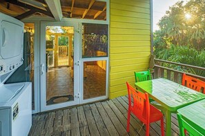 A deck with a table and chairs, a grill, and a sliding glass door leading to an outdoor patio. - Spacious coastal house with outdoor pool, deck & near beach (Placencia)