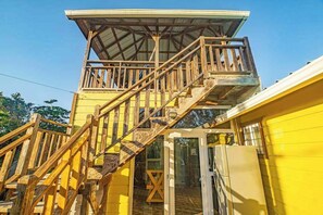 A yellow building with a wooden staircase leading to a covered upper level. - Spacious coastal house with outdoor pool, deck & near beach (Placencia)