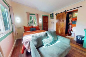 A bedroom with a bed, a chair, a wardrobe, and a bathroom. - Spacious coastal house with outdoor pool, deck & near beach (Placencia)