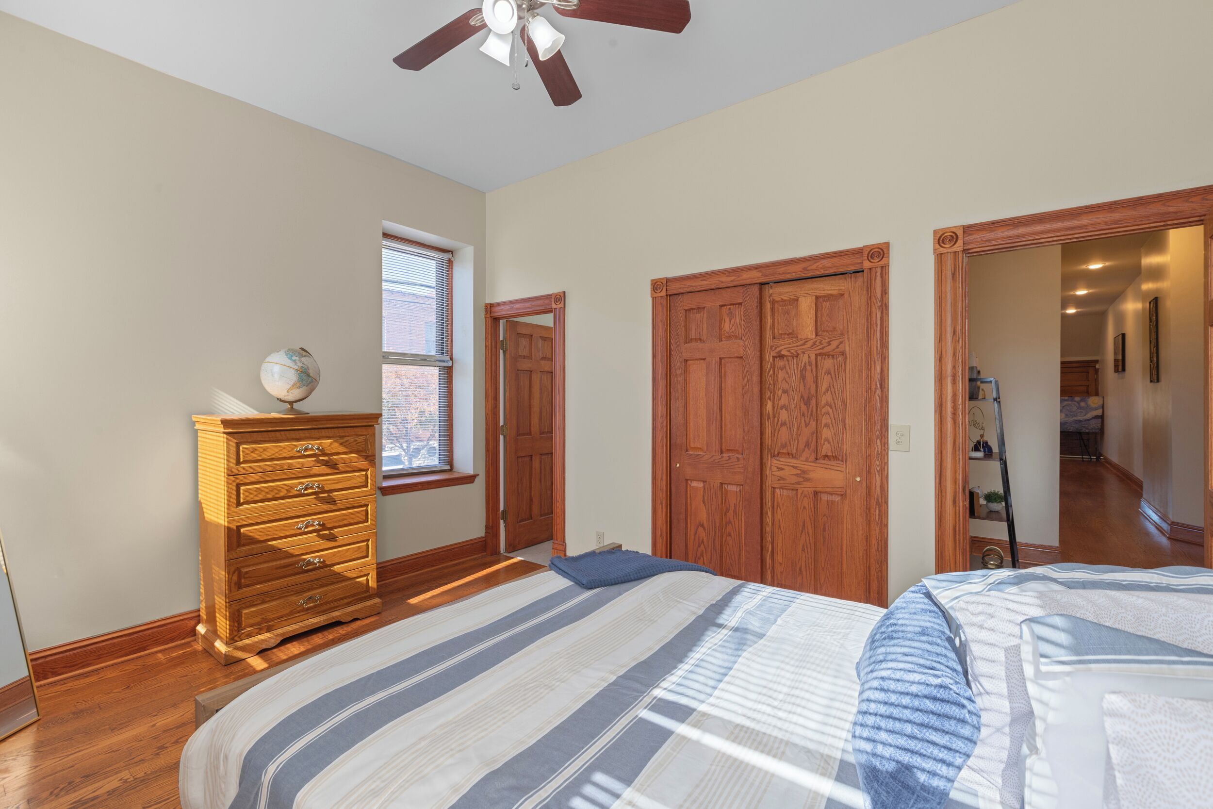 A bedroom with a bed, dresser, and a ceiling fan.