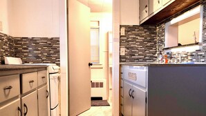 A narrow kitchen with a tiled backsplash, a refrigerator, and a microwave. - Tiny Home Away From Home - Complete Privacy, Peace (Watertown)